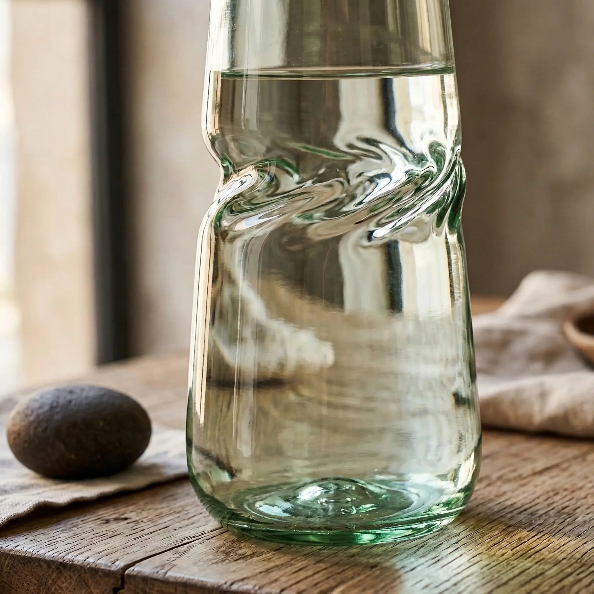 Clear glass VISLA carafe on a wooden surface with a blurred background